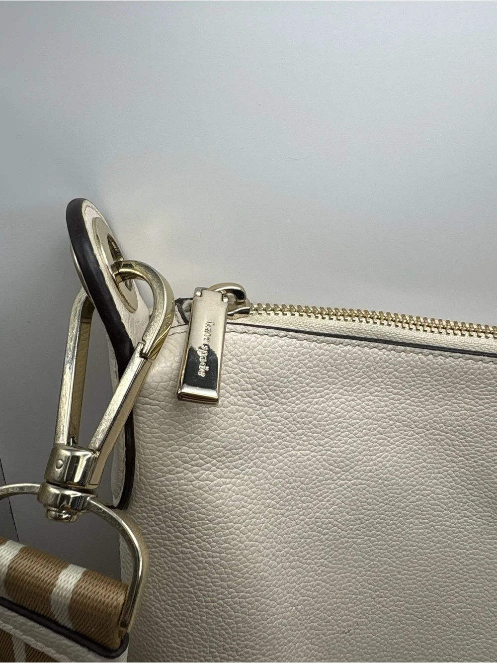 Kate Spade New York cream leather crossbody bag featuring a striped webbing Stra